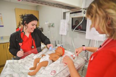 护理专业的学生拿着一个人体模拟婴儿模型.
